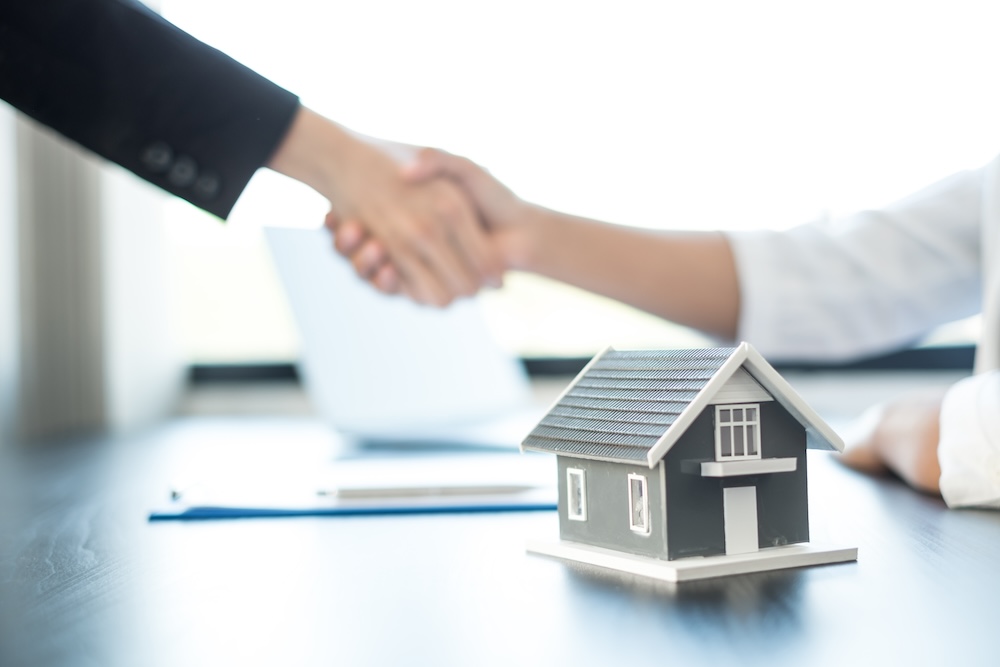 Businessmen and brokers real estate agents shake hand after completing negotiations to buy houses insurance and sign contracts. Home insurance concept. (Businessmen and brokers real estate agents shake hand after completing negotiations to buy houses